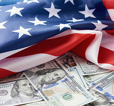 scattered one hundred dollar bills under an American flag