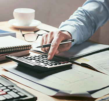 Accountant working at desk with calculator and cup of coffee