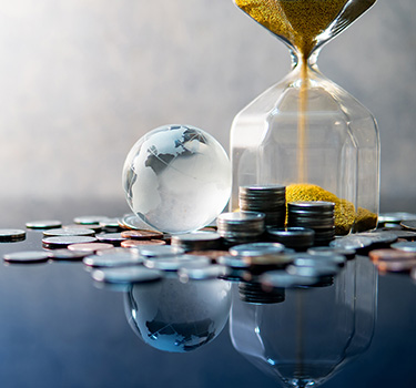 Golden hourglass, coins and glass globe on desk