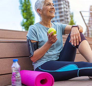 Woman outdoors eating an apple after exercise