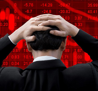 Man holding his head looking at the stock market fall on a computer billboard