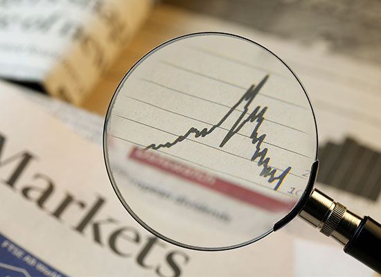 magnifying glass looking at stock market graph