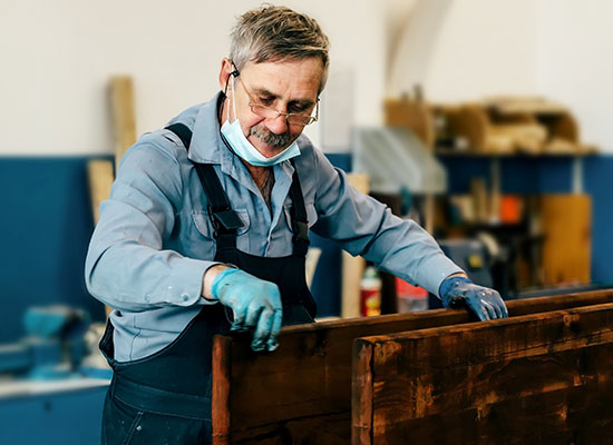 an older gentleman staining a board