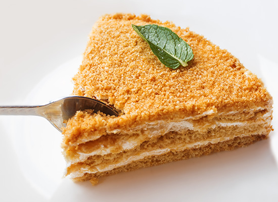 A layered honey cake slice with a spoon cutting into it, symbolizing the impact of IRA early withdrawal on retirement savings