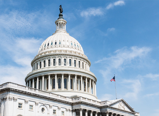 The United States Capitol building, crowned with its distinctive dome, stands majestically against a clear blue sky.