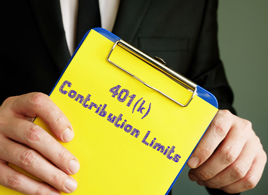 A person in a suit holds a yellow clipboard with the text '401(k) Contribution Limits' written on it