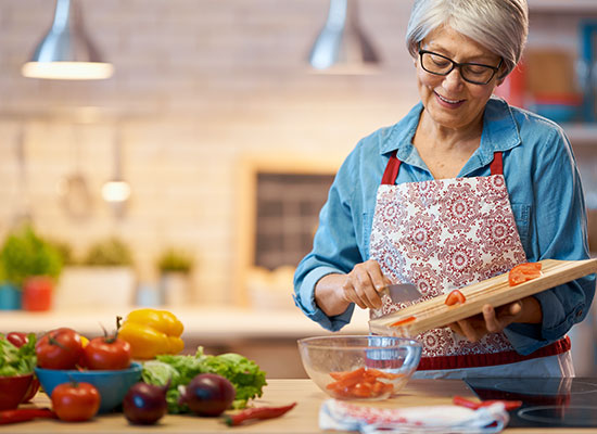 A woman chopping vegetables in her kitchen