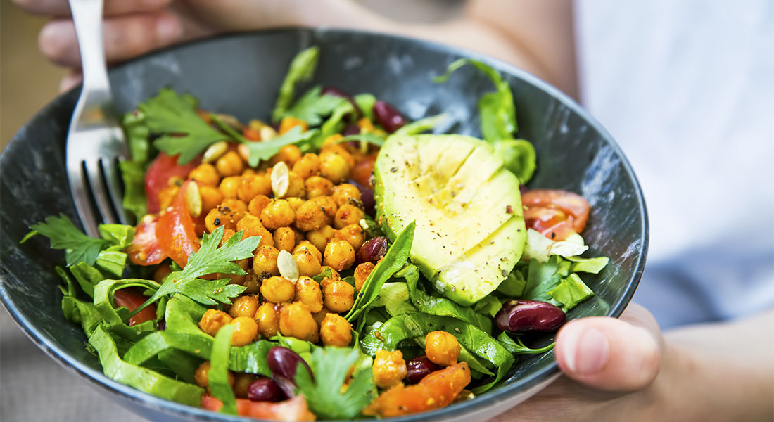 Healthy bowl of salad with chickpeas, olives, avacado, tomatoss and mixed-greens