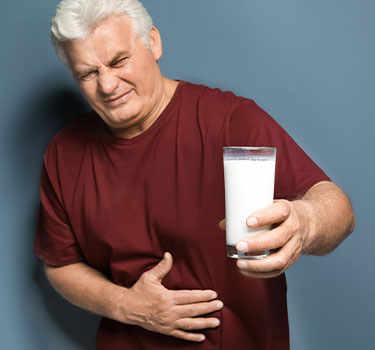 A guy holding his stomach after drinking milk due to being lactose intolerant