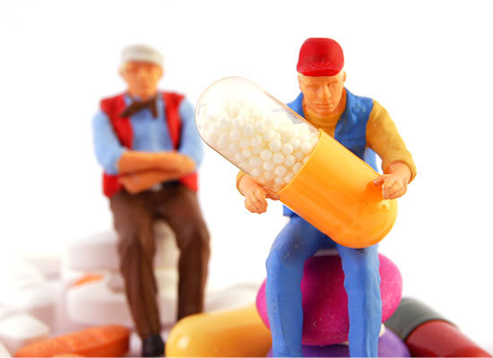 two two figures holding a pill sitting on a pile of pills