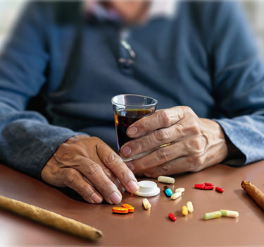 elderly man sitting at a table with different pills to take
