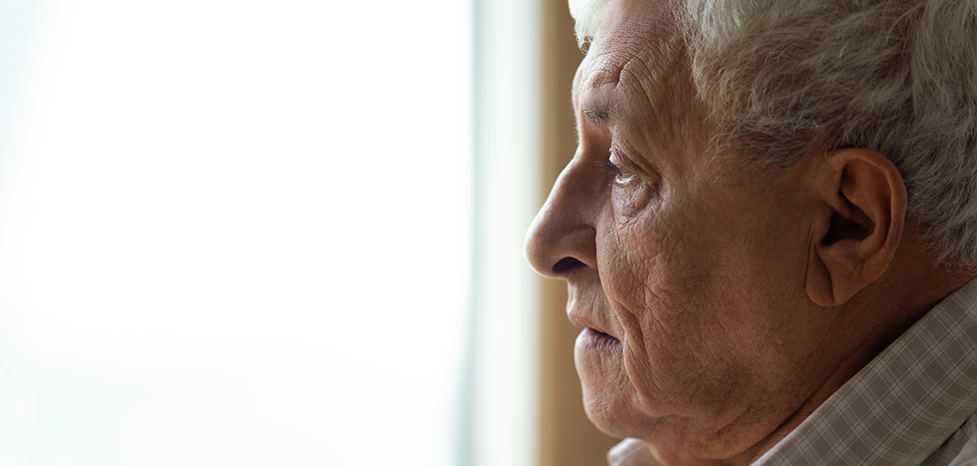 A senior affected by a neurological disorder looking out a window