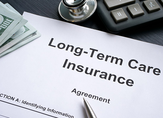 A long-term care insurance agreement is displayed on a desk, accompanied by a stethoscope, calculator, and stacks of money, symbolizing the financial and health considerations involved in such policies.