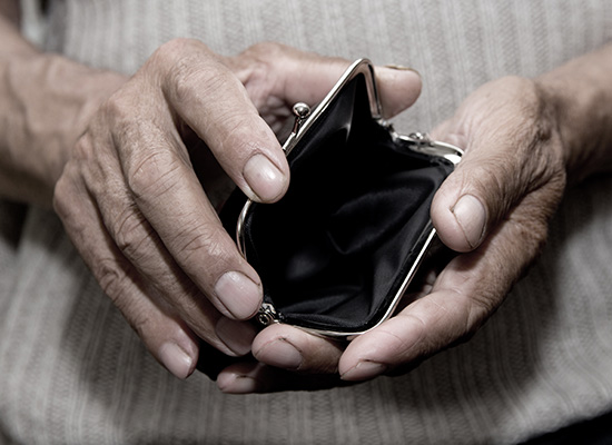 An elderly person holding an empty coin purse, highlighting the financial consequences faced by low-income retirees due to coverage gaps in Medicare and Medicaid.