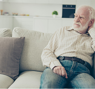 Older man sitting alone on his couch during social isolation