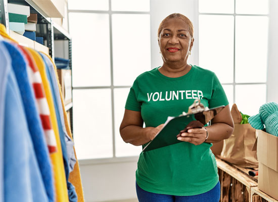 A retiree wearing a 'Volunteer' t-shirt uses a clipboard to track activities, showcasing how volunteering can offer health benefits, social connections, and promote healthy aging