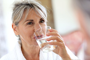 An older woman drinking a glass of water