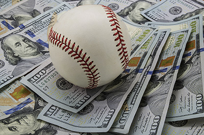 Baseball sitting on hundred dollar bills