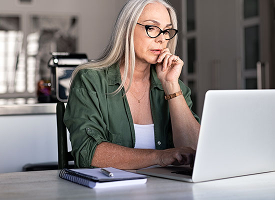 A worried senior woman working on a laptop