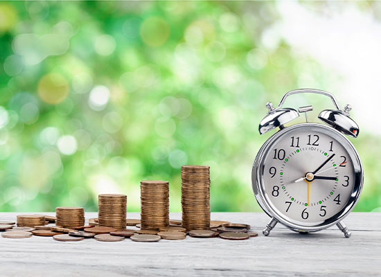 Stacks of coins getting larger standing right next to an alarm clock