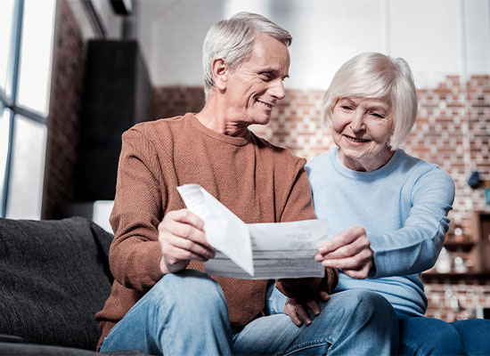 An older man showing his significant other a document with a grin on his face
