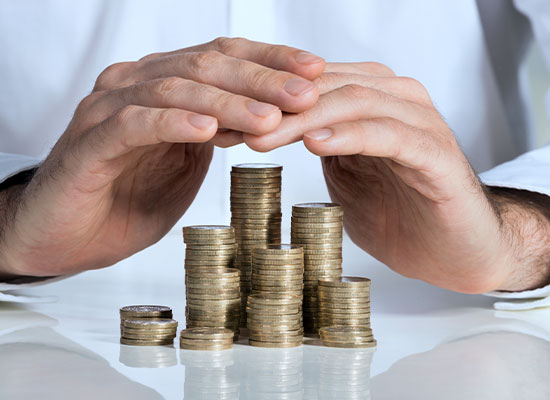 A photo of a man protecting his stacks of coins by holding his hands over them