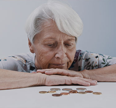 A woman disappointed while looking down at a few coins.