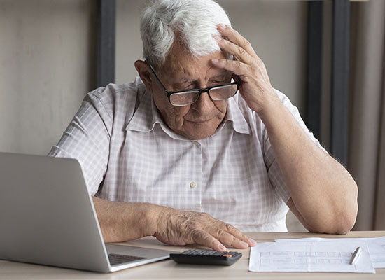 elderly man looking at finances seemingly worried