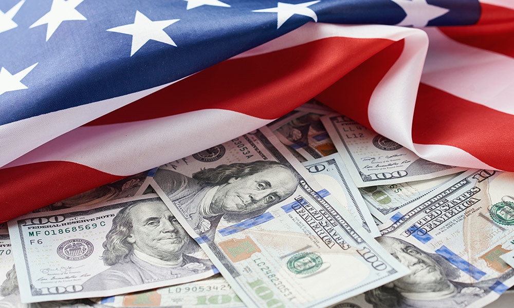 scattered one hundred dollar bills under an American flag