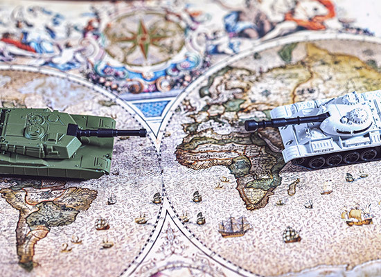two toy tanks on a map pointing at one another