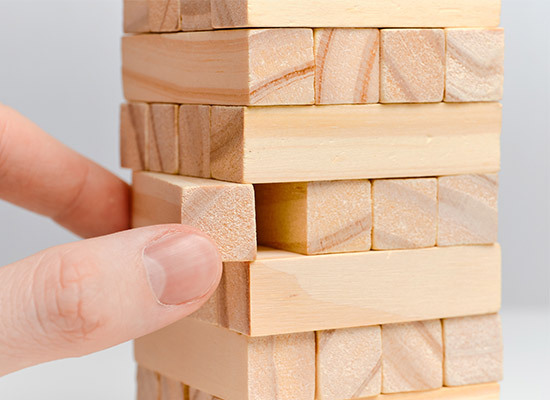 jenga blocks with one being removed by a hand