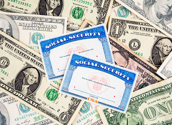 different dollar bills with social security cards on top