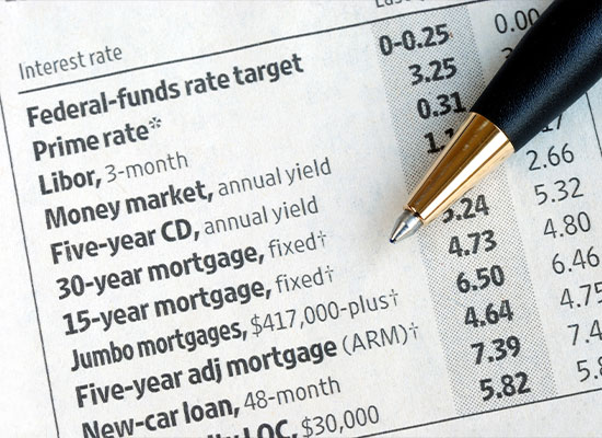 A close-up image of a financial document listing various interest rates, including federal-funds rate and libor, with a pen resting on top.