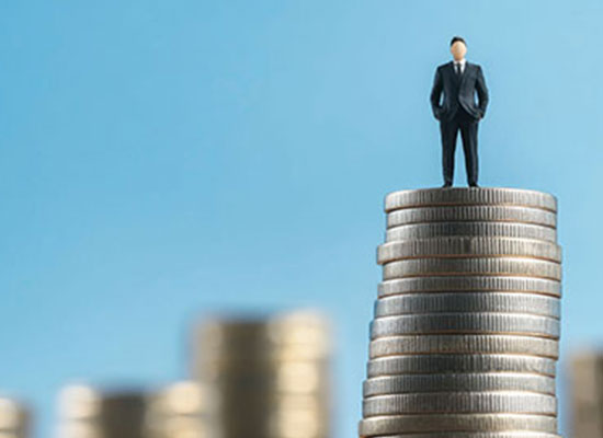 A miniature businessman standing atop a stack of coins, symbolizing retirement planning, 401(k) contribution limits for 2025, and employer matching contributions.