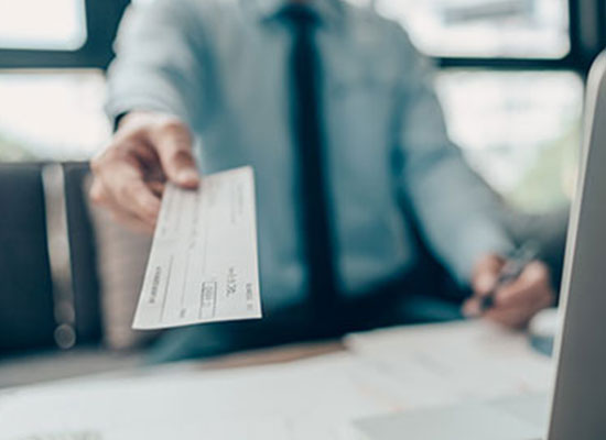 A person handing over a check, illustrating retirement account changes, SECURE 2.0 Act updates, and catch-up contributions for retirement savings.