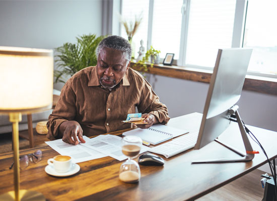 An individual reviews retirement income planning documents at a desk, considering strategies such as safe withdrawal rates, Social Security claiming, annuities and tax-efficient portfolio management.