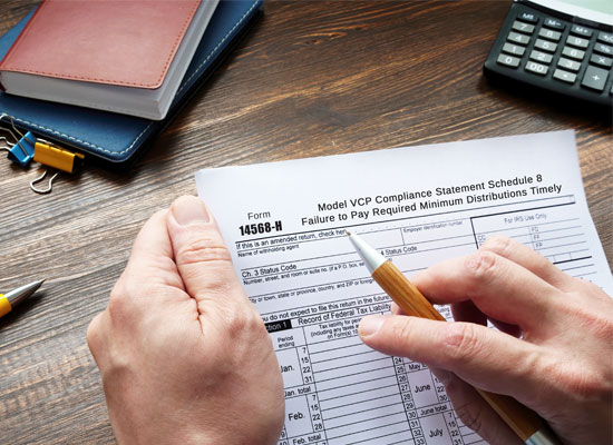 Hands holding a tax form related to penalties for failing to pay required minimum distributions