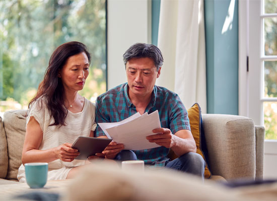A married couple reviewing retirement account documents, focusing on RMD rules, tax impacts, spousal beneficiaries, and qualified charitable distributions under the SECURE 2.0 Act.
