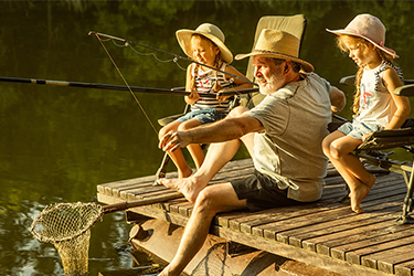 Grandpa fishing with his young granddaughters