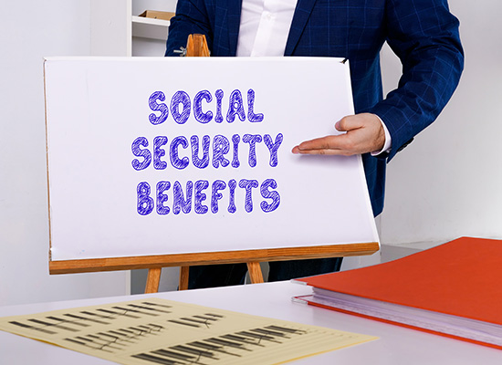 A businessperson points to a whiteboard displaying 'SOCIAL SECURITY BENEFITS' in purple text, illustrating a presentation on retirement benefits.