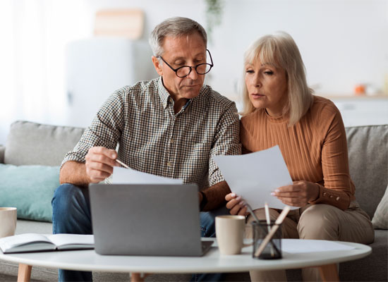 A retirement-age couple reviewing financial documents together, highlighting financial planning, estate planning, and inheritance rights for late-life marriages or second marriages.