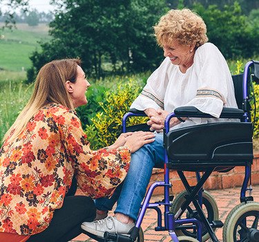 Mother in a wheelchair visiting with her daughter in a garden