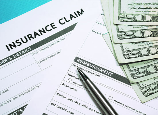 insurance claim form with money and a pen lying on top