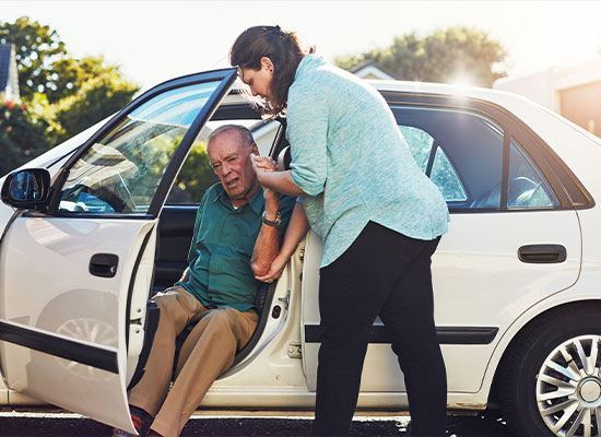 man getting out of car, being aided by a woman