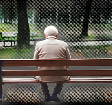 An elderly man sitting alone on a park bench, symbolizing the growing number of Americans aging alone.