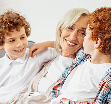 Woman enjoying being a grandmother on the couch with her two ginger grandsons