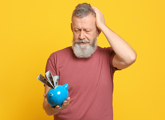 man holding a piggy bank with his other hand placed on his head