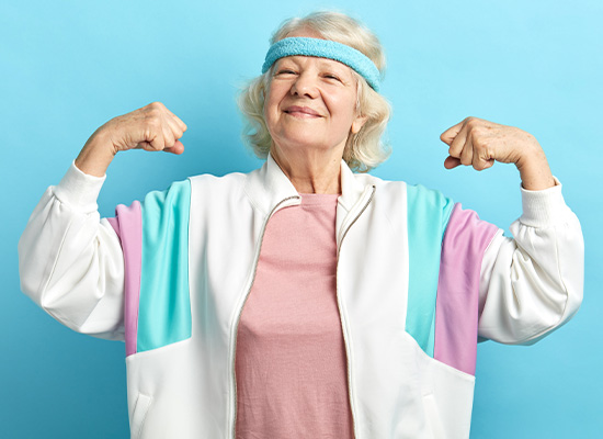 older woman in workout clothes flexing her muscles