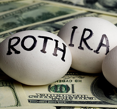 Three eggs sitting on top of hundred dollar bills with the words Roth, IRA and 401k written on them